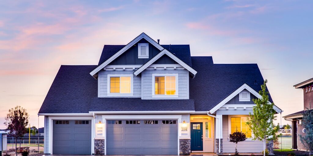 Suburban home at twilight showing prominent shingle roof and double garage