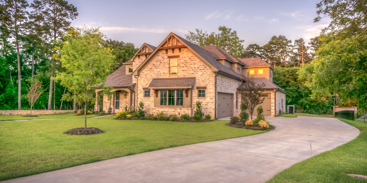 Beautiful stone house with landscaped driveway at sunset