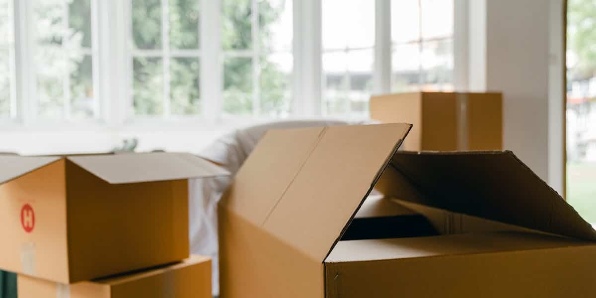 Moving boxes in a bright room with large windows on moving day