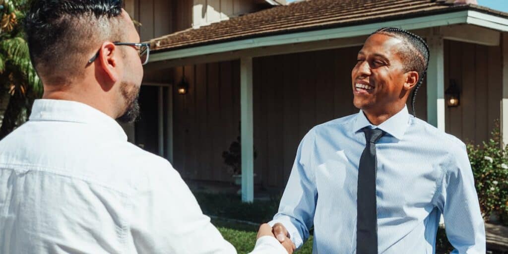Real estate agent shaking hands with buyer outside a home