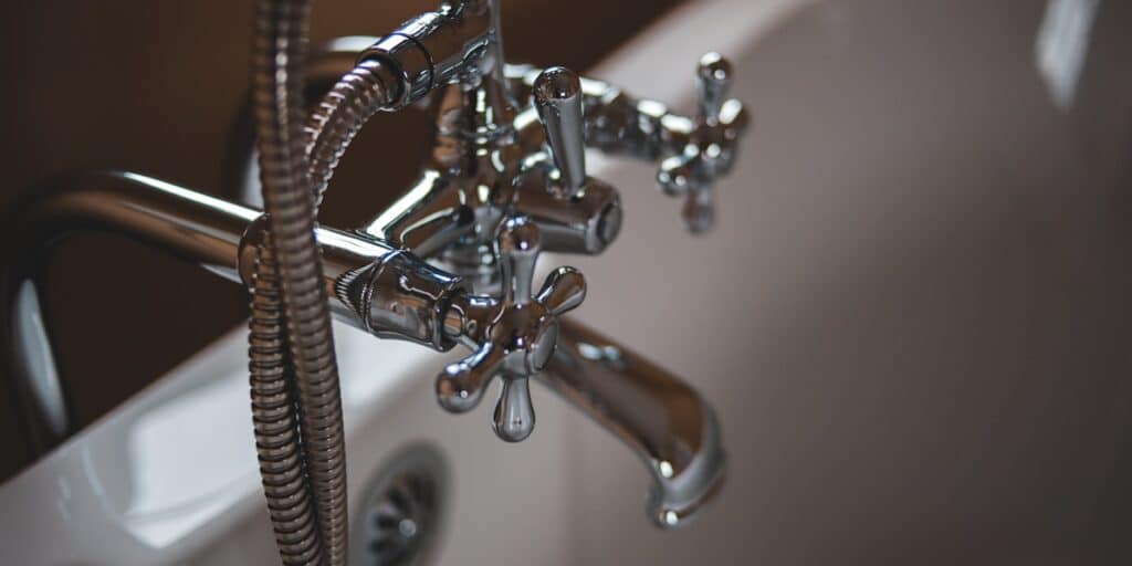 Kitchen faucet and plumbing fixtures being inspected for leaks
